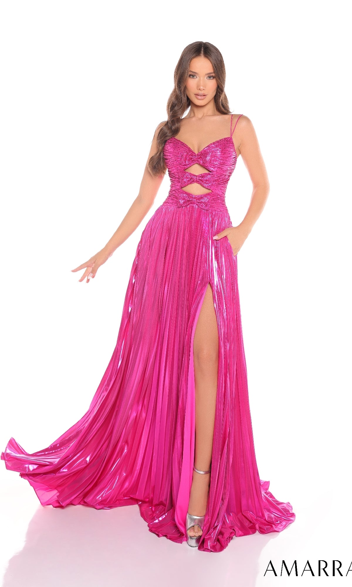 A woman models the Amarra 88435 long prom dress, featuring shiny hot pink metallic fabric, spaghetti straps, a v-neckline, cutout front, high-leg slit, and flowing skirt.